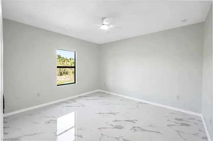 Empty room featuring ceiling fan and light marble finish floors