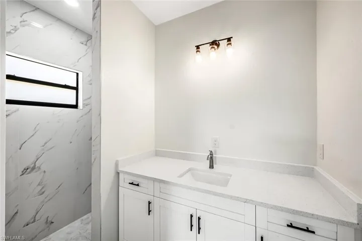Bathroom with vanity and a marble finish shower