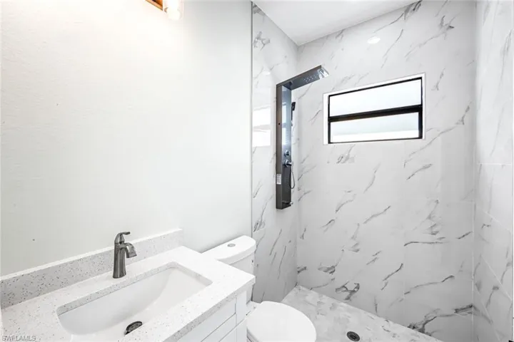 Full bath with vanity and a marble finish shower