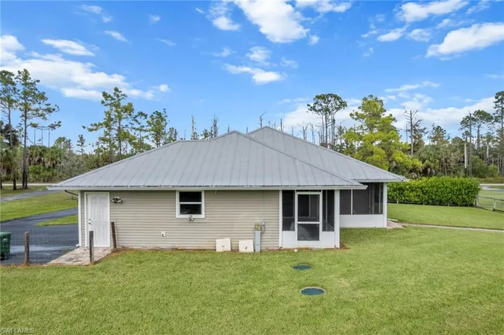 Back of property with a yard, a metal roof, and a sunroom