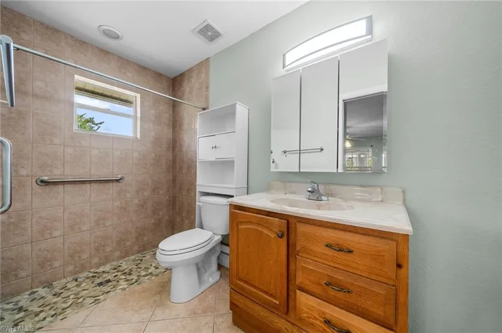 Bathroom featuring vanity, light tile patterned floors, and a stall shower