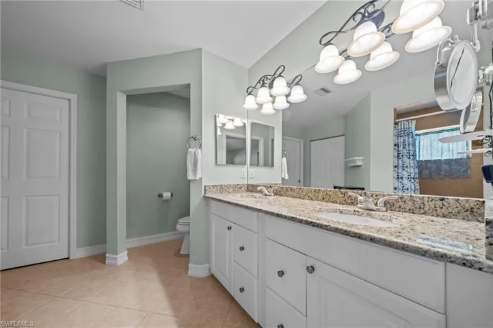 Full bath with double vanity, curtained shower, and light tile patterned floors