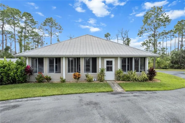 View of front of guest house with a sunroom, a front lawn, and a metal roof