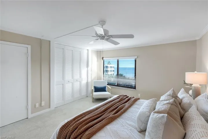Carpeted bedroom with crown molding, a closet, and a ceiling fan