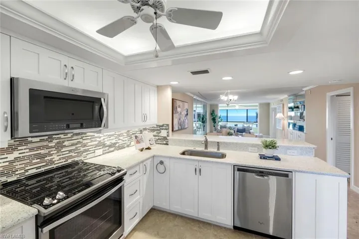 Kitchen featuring stainless steel appliances, white cabinets, a peninsula, open floor plan, and backsplash