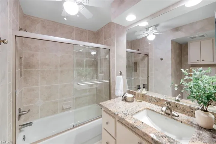 Full bath featuring a ceiling fan, vanity, and shower / bath combination with glass door