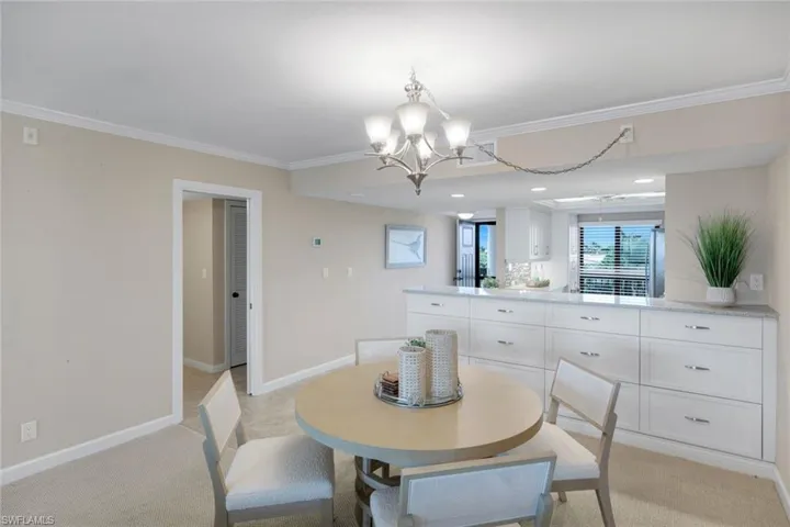 Dining space with crown molding, light colored carpet, a chandelier, and recessed lighting