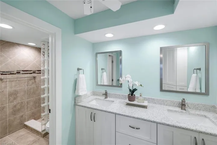 Full bathroom featuring double vanity, walk in shower, a ceiling fan, and recessed lighting