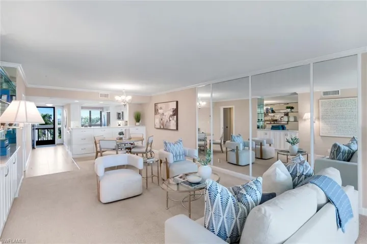 Living area with light carpet, ornamental molding, and a chandelier
