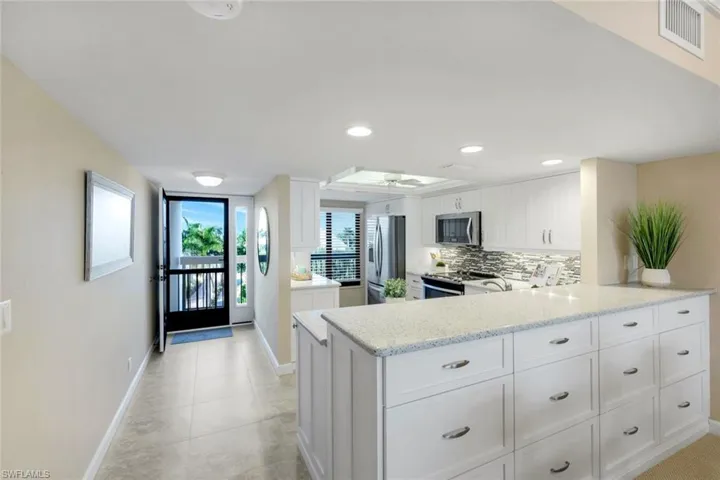 Kitchen featuring white cabinetry, a peninsula, light stone counters, and recessed lighting