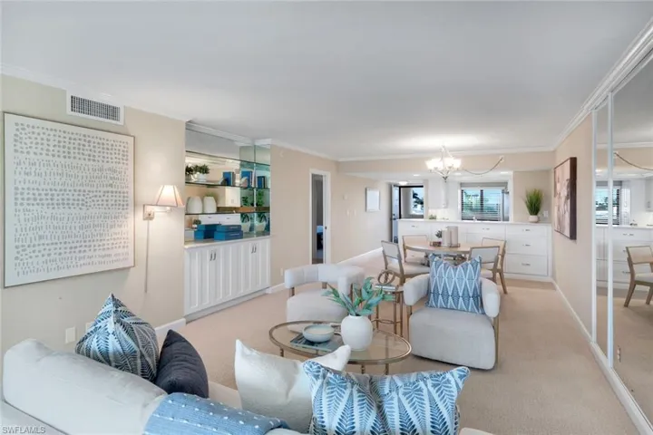 Living room with light carpet, a chandelier, and ornamental molding