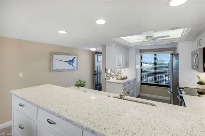 Kitchen with white cabinets, light stone counters, stainless steel appliances, recessed lighting, and tasteful backsplash