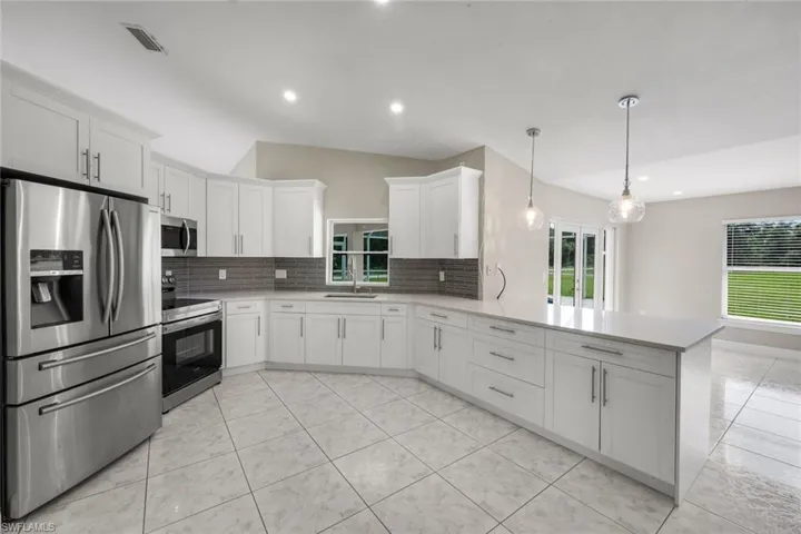 Kitchen featuring white cabinetry, stainless steel appliances, a tile backsplash, and a large island with pendant lighting