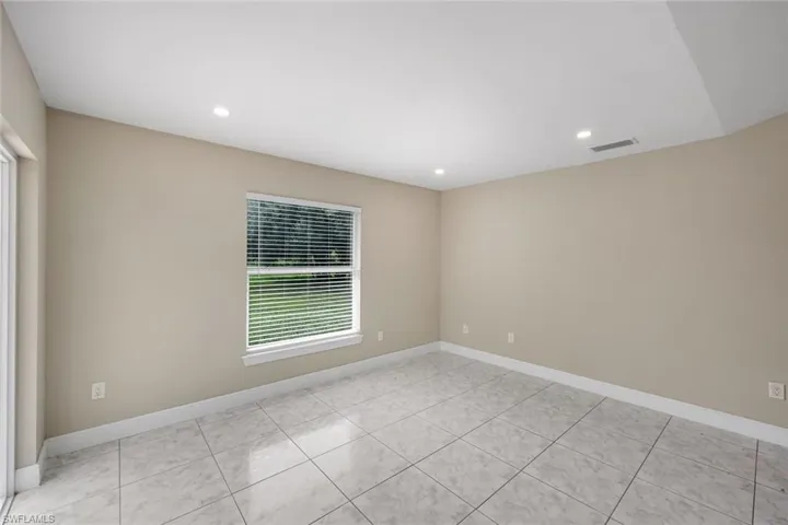 Spacious room featuring tile flooring, neutral wall tones, recessed lighting, and a large window with blinds