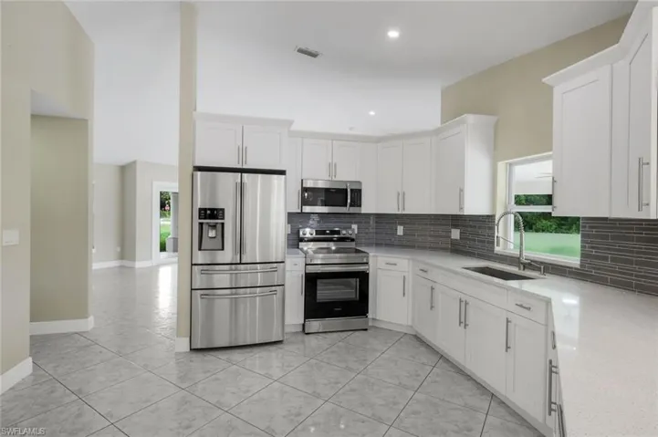 Kitchen featuring white cabinetry, stainless steel appliances, a grey tile backsplash, white countertops, and tile flooring