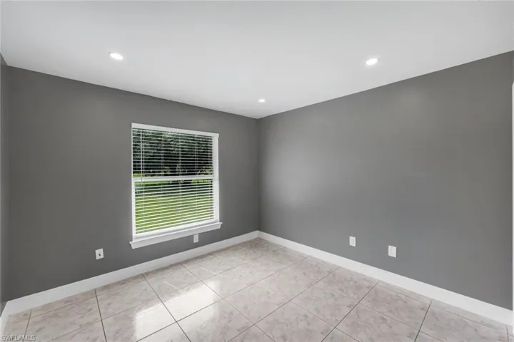 Recessed lighting, tile flooring, window with blinds, white trim, and gray walls