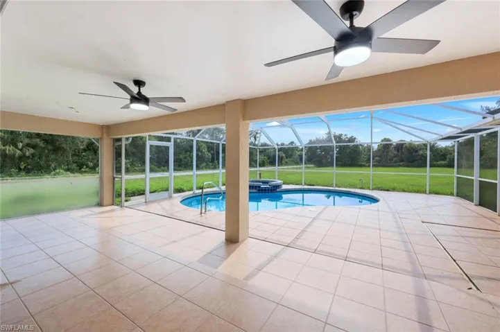 Screened lanai featuring a swimming pool, hot tub, tile flooring, and two ceiling fans