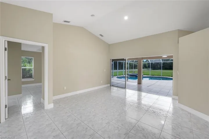Vaulted ceilings enhance this room featuring light-toned tile flooring and recessed lighting
