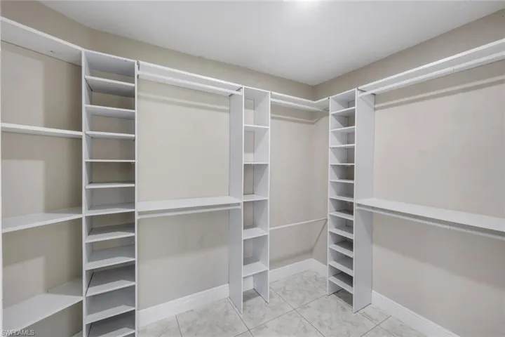 Custom closet system with multiple shelving units, hanging rods, and tiled flooring
