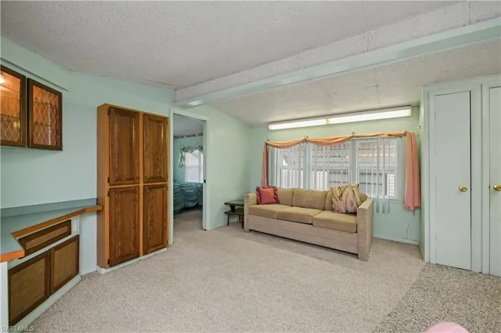 Living area featuring light carpet and a textured ceiling