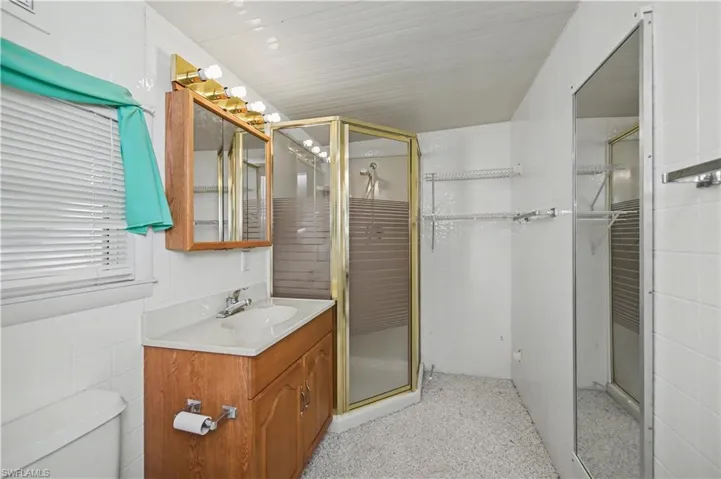 Full bathroom with a stall shower, vanity, and tile walls