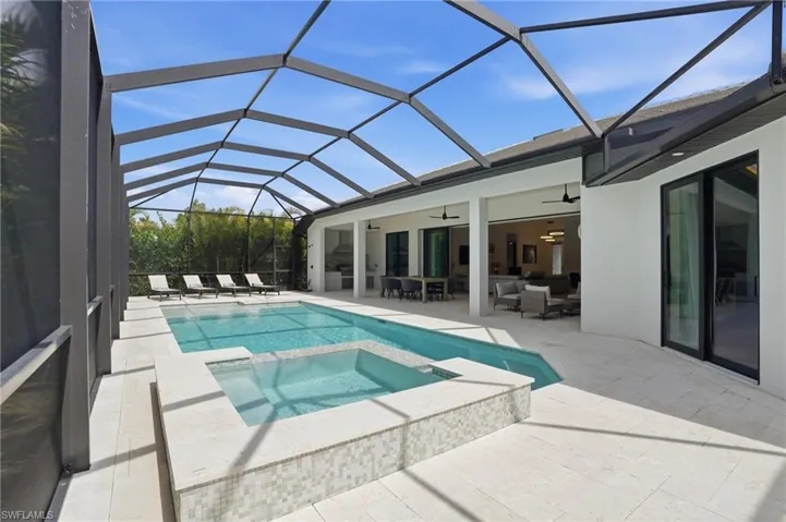 Combined pool / hot tub with a patio area, a sunroom, outdoor lounge area, and glass enclosure