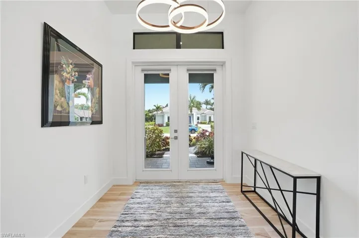 Doorway to outside featuring french doors, wood finished floors, and suspended lighting
