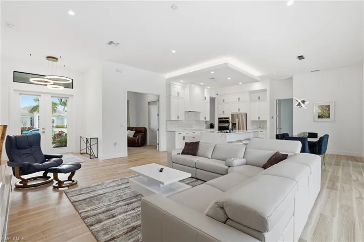 Living room featuring light wood-style flooring, recessed lighting, and french doors