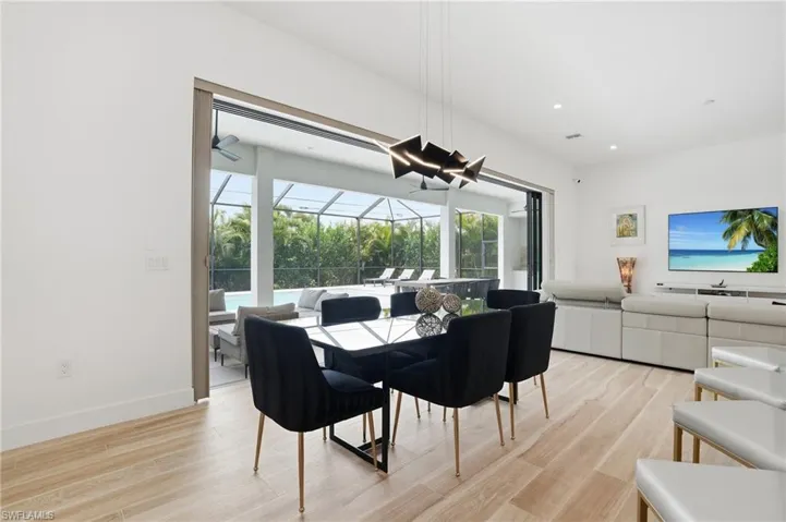 Dining room featuring a sunroom, light wood-type flooring, and recessed lighting