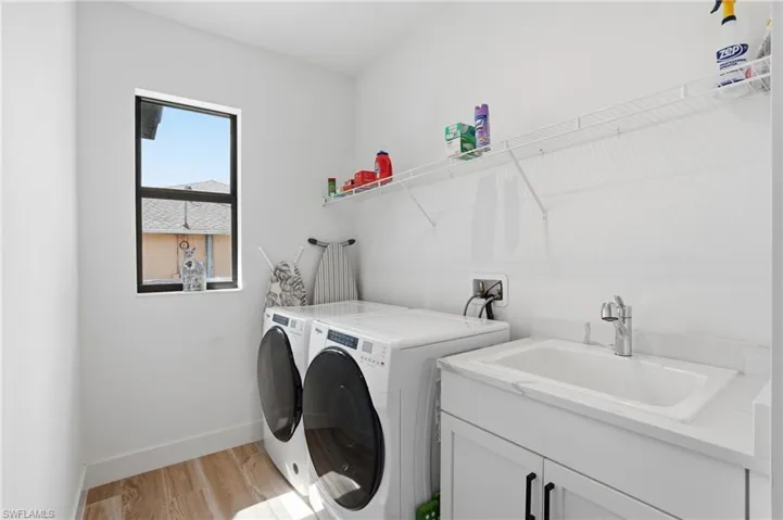 Laundry room with light wood finished floors, separate washer and dryer, and cabinet space