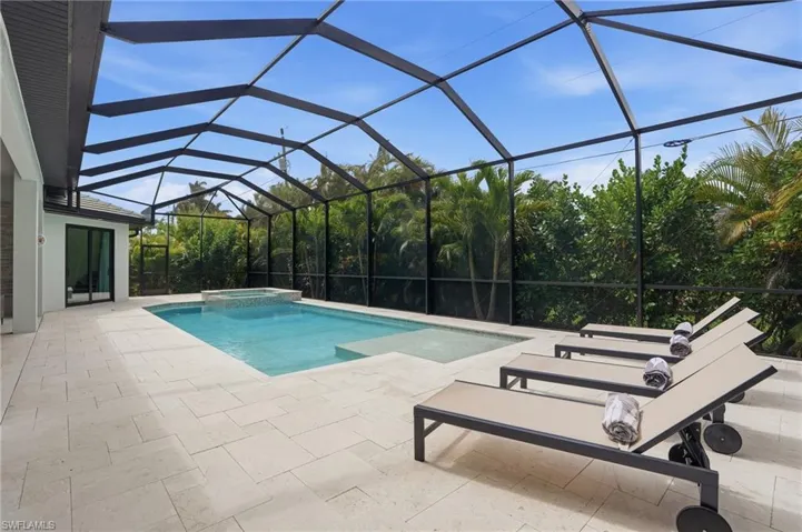 Combined pool / hot tub with a sunroom, a patio area, and glass enclosure