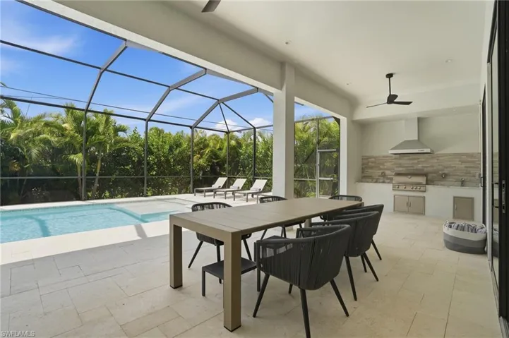 View of patio / terrace with an outdoor kitchen / dining area, a sunroom, a lanai, a ceiling fan, and an outdoor pool