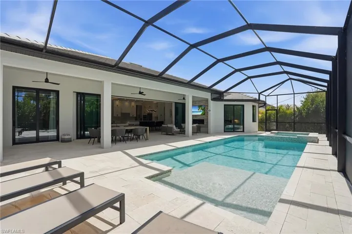 Relaxing pool / spa featuring a sunroom, a patio, glass enclosure, and outdoor lounge area