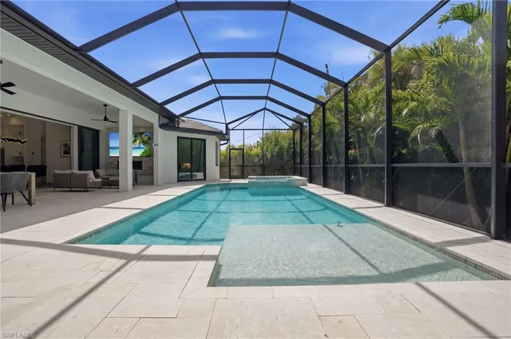 Relaxing pool / spa with a patio, an outdoor lounge area, a sunroom, and glass enclosure