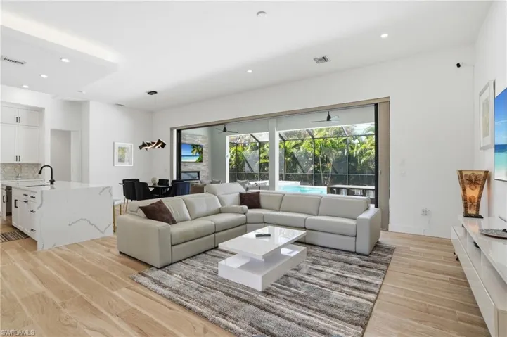 Living room featuring a sunroom, light wood-type flooring, and recessed lighting