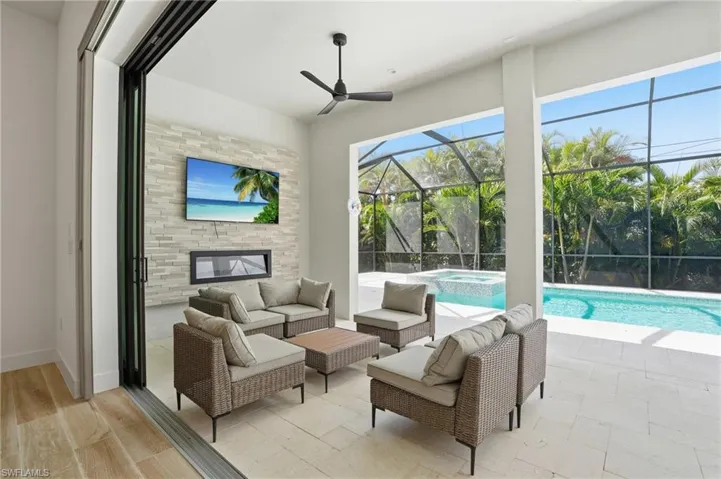 View of patio with a sunroom, a pool with connected hot tub, a ceiling fan, glass enclosure, and outdoor furniture