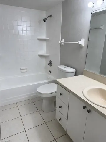 Bathroom featuring a white bathtub with subway tile surround, corner shelving, and a shower head