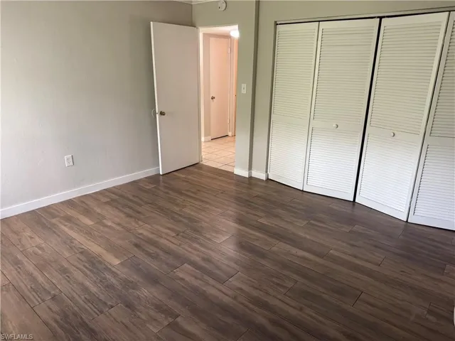 Wood-finish flooring throughout, featuring a series of white louvered bifold doors, and a neutral wall color with white baseboards