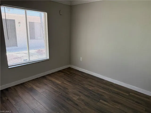 Room featuring wood-finish flooring, neutral wall paint, and white baseboards