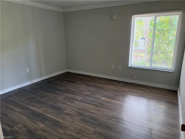 Interior room featuring dark wood-finish flooring, light gray wall paint, and white baseboards