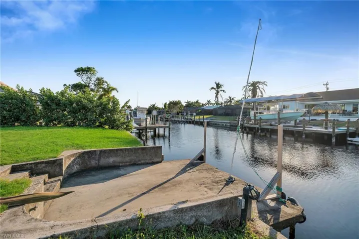 View of dock with a lawn and a water view