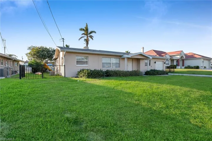 View of front facade featuring central AC unit, a front lawn, and a garage