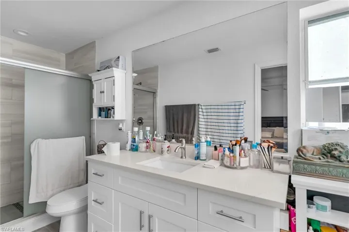 Bathroom featuring walk in shower, vanity, and toilet