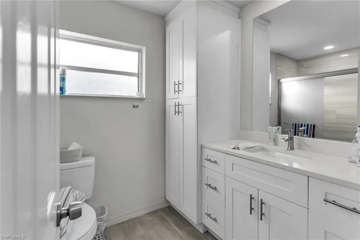 Bathroom featuring wood-type flooring, vanity, toilet, and walk in shower