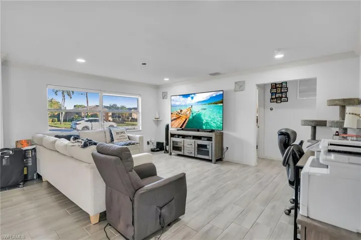 Living room with light wood-type flooring and crown molding