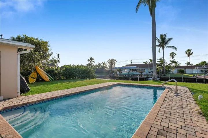 View of swimming pool with a playground and a lawn