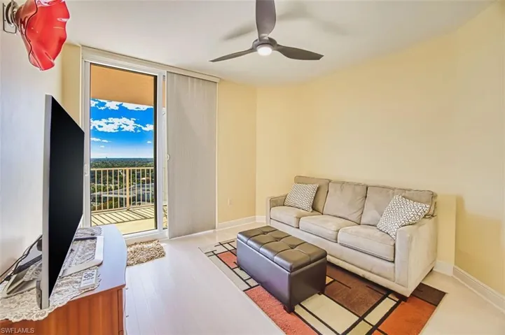 Living area with expansive windows, wood finished floors, and ceiling fan