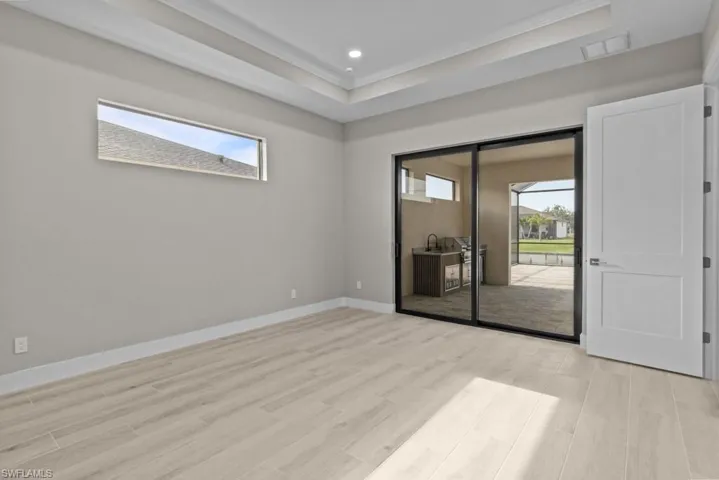 Master bed room featuring crown molding, light wood finished floors, baseboards, recessed lighting, and a tray ceiling