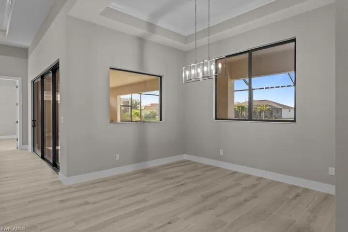 Dining Room finished floors, a raised ceiling, a chandelier, and baseboards