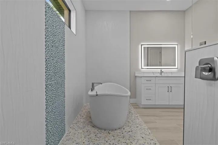 Full bath featuring wood finished floors, vanity, and a soaking tub